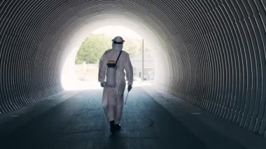 Koruyucu giysili bir adam metro tünelini antiseptik spreyle dezenfekte ediyor. Coronavirus covid-19 hastalığından dolayı yüzey tedavisi. Virüs salgını ve koruma kavramları.