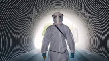 Koruyucu giysili bir adam metro tünelini antiseptik spreyle dezenfekte ediyor. Coronavirus covid-19 hastalığından dolayı yüzey tedavisi. Virüs salgını ve koruma kavramları.