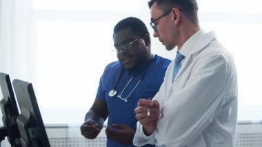 Doktor ve cerrah hastane ofisinde bilgisayar teknolojisi kullanıyorlardı. Klinikte sağlık çalışanları. Gün ışığı. Sağlık, tıp, takım çalışması kavramları.