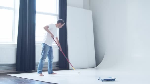Young Man Painting Cyclorama Photo Studio Using Roller Painter White — Stock Video