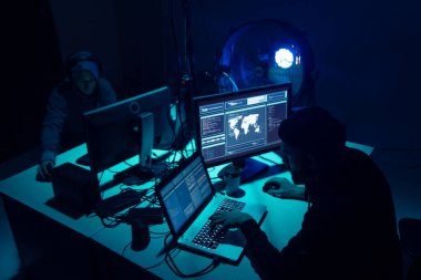 Aranan hackerlar virüs fidye yazılımını bodrumdaki bilgisayar ve dizüstü bilgisayarlarla kodluyorlar. Siber saldırı, sistem kırma ve kötü amaçlı yazılım kavramı.