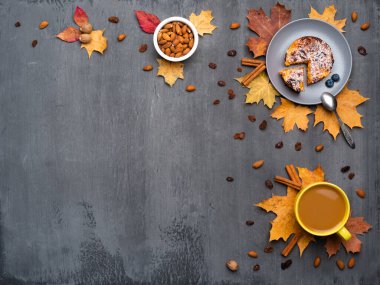 Mevsimlik sonbahar geçmişi. Renkli akçaağaç yaprakları ve bir fincan sıcak içecek, kahve, latte veya kapuçino, hindistan cevizi, kek ve tarçın..