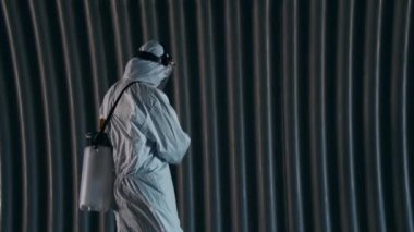 Koruyucu giysili bir adam metro tünelini antiseptik spreyle dezenfekte ediyor. Coronavirus covid-19 hastalığından dolayı yüzey tedavisi. Virüs salgını ve koruma kavramları.