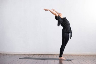 Sınıfta yoga yapan genç ve formda bir kadın. Gün ışığında esneme egzersizi. Spor, spor, sağlık hizmetleri ve yaşam tarzı kavramları.