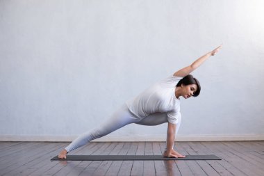 Sınıfta yoga yapan genç ve formda bir kadın. Gün ışığında esneme egzersizi. Spor, spor, sağlık hizmetleri ve yaşam tarzı kavramları.
