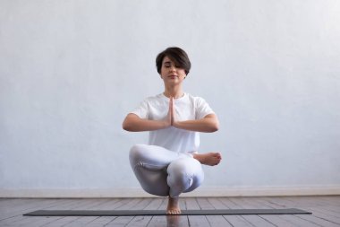 Sınıfta yoga yapan genç ve formda bir kadın. Gün ışığında esneme egzersizi. Spor, spor, sağlık hizmetleri ve yaşam tarzı kavramları.