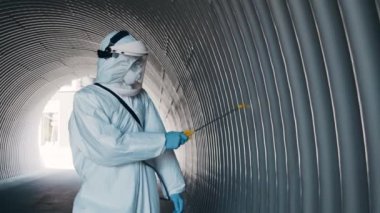 Koruyucu giysili bir adam metro tünelini antiseptik spreyle dezenfekte ediyor. Coronavirus covid-19 hastalığından dolayı yüzey tedavisi. Virüs salgını ve koruma kavramları.