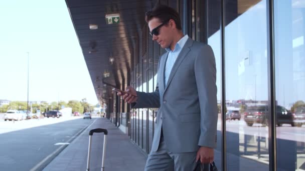 优雅的商人在机场使用智能手机 穿正装的年轻邮务企业家 公务旅行和旅行概念 — 图库视频影像