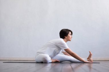 Sınıfta yoga yapan genç ve formda bir kadın. Gün ışığında esneme egzersizi. Spor, spor, sağlık hizmetleri ve yaşam tarzı kavramları.