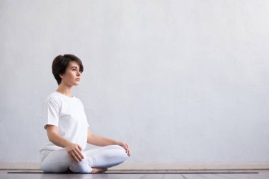 Sınıfta yoga yapan genç ve formda bir kadın. Gün ışığında esneme egzersizi. Spor, spor, sağlık hizmetleri ve yaşam tarzı kavramları.