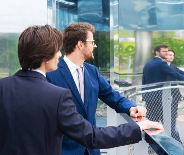 Takım çalışması ve iş konsepti. Resmi olarak kendine güvenen işadamları ofis binası önünde bankacılık ve finans piyasaları hakkında konuşuyorlar..