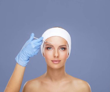Genç bir kadının güzel yüzüne iğne yapan bir doktor. Estetik ameliyat, cilt gerdirme ve estetik tıp konsepti.