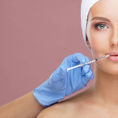 Genç bir kadının güzel yüzüne iğne yapan bir doktor. Estetik ameliyat, cilt gerdirme ve estetik tıp konsepti.