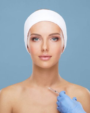 Genç bir kadının güzel yüzüne iğne yapan bir doktor. Estetik ameliyat, cilt gerdirme ve estetik tıp konsepti.