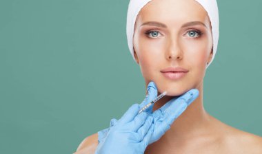 Genç bir kadının güzel yüzüne iğne yapan bir doktor. Estetik ameliyat, cilt gerdirme ve estetik tıp konsepti.