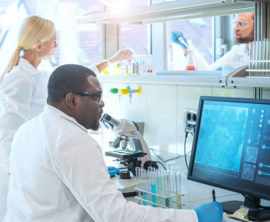 Laboratuvarda çalışan bir bilim adamı. Doktorlar tıbbi araştırma yapıyor. Laboratuvar aletleri: mikroskop, test tüpleri, ekipmanlar. Coronavirus, kimya, bilim, deneyler ve sağlık konsepti. Gün ışığı ve