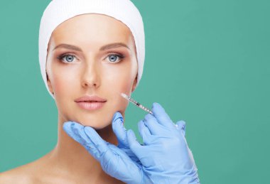 Genç bir kadının güzel yüzüne iğne yapan bir doktor. Estetik ameliyat, cilt gerdirme ve estetik tıp konsepti.
