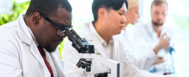 Laboratuvarda çalışan bilim adamları ve öğrenciler. Doktor stajyerlere araştırma yapmayı öğretiyor. Laboratuvar aletleri: mikroskop, test tüpleri, ekipmanlar. Biyoteknoloji, kimya, bakteriyoloji, viroloji, DNA