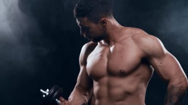 Siyah arka planda formda ve sportif vücut geliştirici. Dambıl kullanarak vücut geliştirici eğitimi. Spor ve spor kavramları.