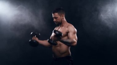 Siyah arka planda formda ve sportif vücut geliştirici. Dambıl kullanarak vücut geliştirici eğitimi. Spor ve spor kavramları.