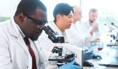 Laboratuvarda çalışan bilim adamları ve öğrenciler. Doktor stajyerlere araştırma yapmayı öğretiyor. Laboratuvar aletleri: mikroskop, test tüpleri, ekipmanlar. Biyoteknoloji, kimya, bakteriyoloji, viroloji, DNA