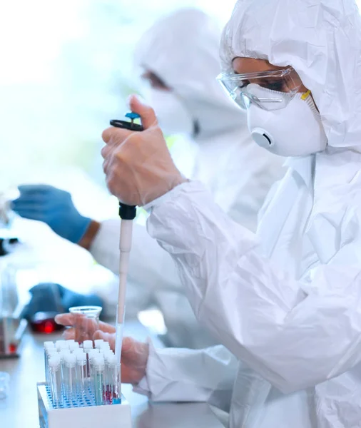 身穿防护服和戴口罩的科学家使用实验室设备在研究实验室工作 显微镜 感染和疫苗发现概念 — 图库照片