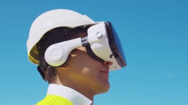 İnşaat alanının önünde sanal gerçeklik teknolojileri kullanarak VR kasklı profesyonel bir inşaatçı. Ofis binası ve vinç arka planı. Emlak ve yatırım kavramları