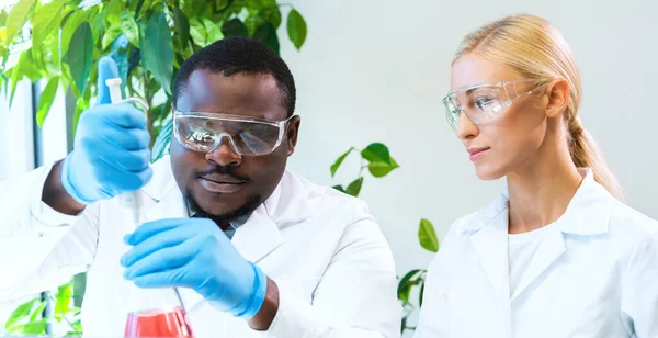 Scientist and students working in lab. Doctor teaching interns to make blood analyzing research. Laboratory tools: microscope, test tubes, equipment. Coronavirus, chemistry, bacteriology, virology and