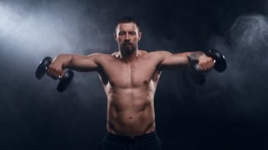 Siyah arka planda formda ve sportif vücut geliştirici. Dambıl kullanarak vücut geliştirici eğitimi. Spor ve spor kavramları.