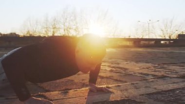 Genç ve zinde bir adam dışarıda akşam antrenmanı yapıyor. Şehir günbatımı geçmişi. Spor ve spor kavramları.