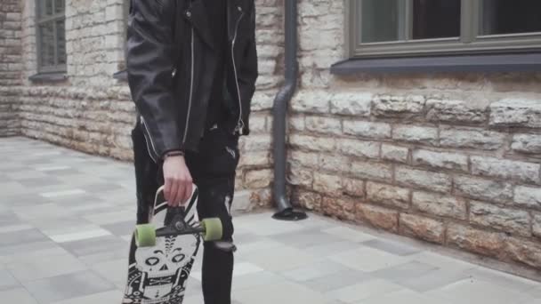 スケートボードの屋外に乗ってスタイリッシュな十代の若者の肖像画 ストリートにスケートボードを持つ10代 スポーツとサブカルチャーの概念 — ストック動画