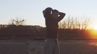 Genç ve zinde bir adam dışarıda akşam antrenmanı yapıyor. Şehir günbatımı geçmişi. Spor ve spor kavramları.