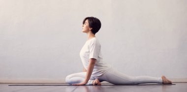 Sınıfta yoga yapan genç ve formda bir kadın. Gün ışığında esneme egzersizi. Spor, spor, sağlık hizmetleri ve yaşam tarzı kavramları.