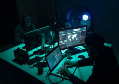 Aranan hackerlar virüs fidye yazılımını bodrumdaki bilgisayar ve dizüstü bilgisayarlarla kodluyorlar. Siber saldırı, sistem kırma ve kötü amaçlı yazılım kavramı.