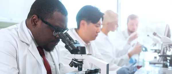 Scientist and students working in lab. Doctor teaching interns to make analyzing research. Laboratory tools: microscope, test tubes, equipment. Biotechnology, chemistry, bacteriology, virology, dna
