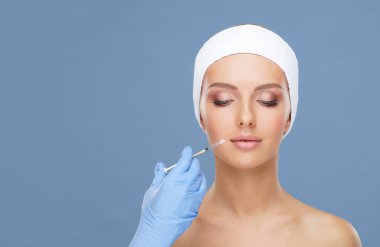 Genç bir kadının güzel yüzüne iğne yapan bir doktor. Estetik ameliyat, cilt gerdirme ve estetik tıp konsepti.