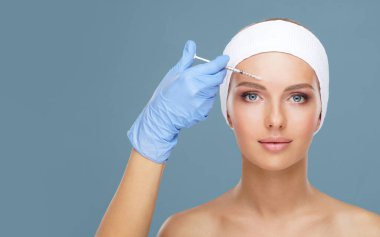 Genç bir kadının güzel yüzüne iğne yapan bir doktor. Estetik ameliyat, cilt gerdirme ve estetik tıp konsepti.