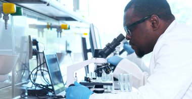 Laboratuvarda çalışan bir bilim adamı. Doktorlar tıbbi araştırma yapıyor. Laboratuvar aletleri: mikroskop, test tüpleri, ekipmanlar. Biyoteknoloji, kimya, bilim, deneyler ve sağlık konsepti. Gün ışığı ve