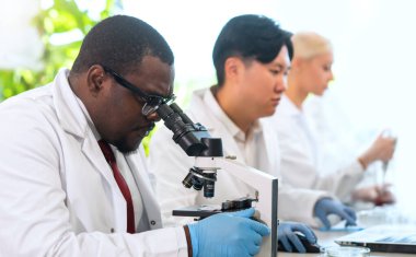 Laboratuvarda çalışan bilim adamları ve öğrenciler. Doktor stajyerlere araştırma yapmayı öğretiyor. Laboratuvar aletleri: mikroskop, test tüpleri, ekipmanlar. Biyoteknoloji, kimya, bakteriyoloji, viroloji, DNA