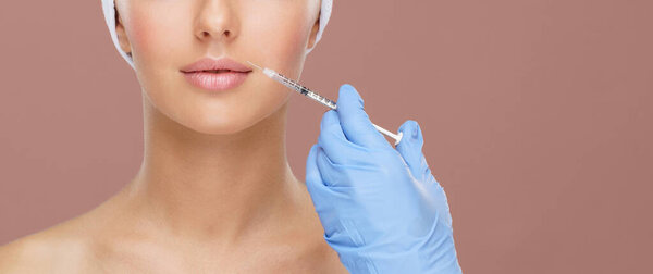 Doctor injecting in a beautiful face of a young woman. Plastic surgery, skin lifting and aesthetic medicine concept.