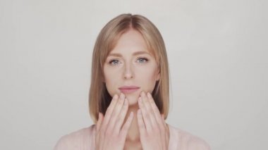 Cilt bakımı kremi süren genç, güzel ve doğal sarışın kadının stüdyo portresi. Yüz gerdirme, kozmetik ve makyaj konsepti.