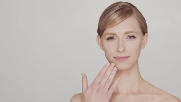 若いのスタジオの肖像画 スキンケアクリームを適用する美しく 自然なブロンドの女性 顔の持ち上げ 化粧品 化粧品のコンセプト — ストック動画