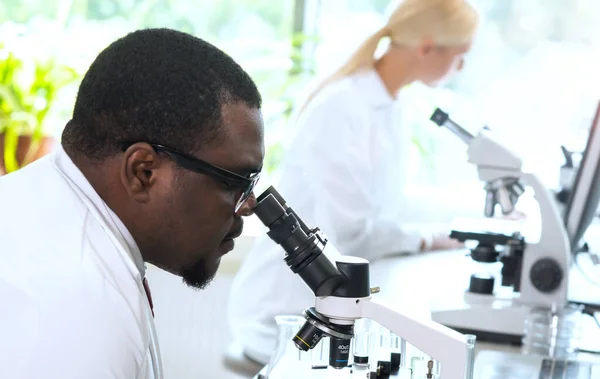 Scientist and students working in lab. Doctor teaching interns to make blood analyzing research. Laboratory tools: microscope, test tubes, equipment. Biotechnology, chemistry, bacteriology, virology