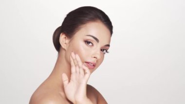 Beyaz arka planda genç ve güzel esmer bir kadının stüdyo portresi. Cilt bakımı ve sağlık kavramları.