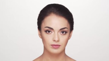 Beyaz arka planda genç ve güzel esmer bir kadının stüdyo portresi. Cilt bakımı ve sağlık kavramları.