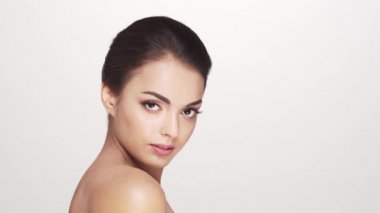 Beyaz arka planda genç ve güzel esmer bir kadının stüdyo portresi. Cilt bakımı ve sağlık kavramları.