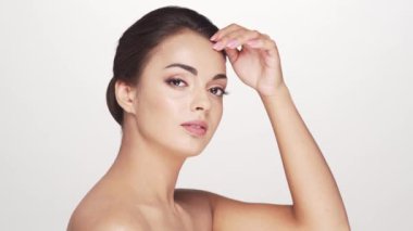 Beyaz arka planda genç ve güzel esmer bir kadının stüdyo portresi. Cilt bakımı ve sağlık kavramları.