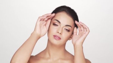 Beyaz arka planda genç ve güzel esmer bir kadının stüdyo portresi. Cilt bakımı ve sağlık kavramları.