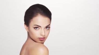 Beyaz arka planda genç ve güzel esmer bir kadının stüdyo portresi. Cilt bakımı ve sağlık kavramları.