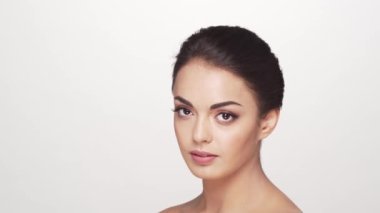 Beyaz arka planda genç ve güzel esmer bir kadının stüdyo portresi. Cilt bakımı ve sağlık kavramları.